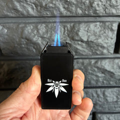 Hand holding a black lighter with a brand logo, igniting it against a stone wall.