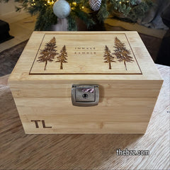 Wooden box with engraved trees and initials, placed in front of a decorated Christmas tree.