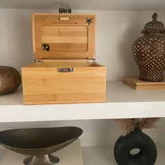 The OG smell proof lockable Bzz box sits on a shelf in a luxury abode, beside several decorative artifacts.